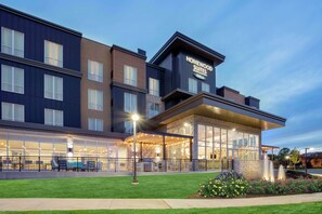 A hotel with a modern design, featuring a covered outdoor seating area and a landscaped garden.