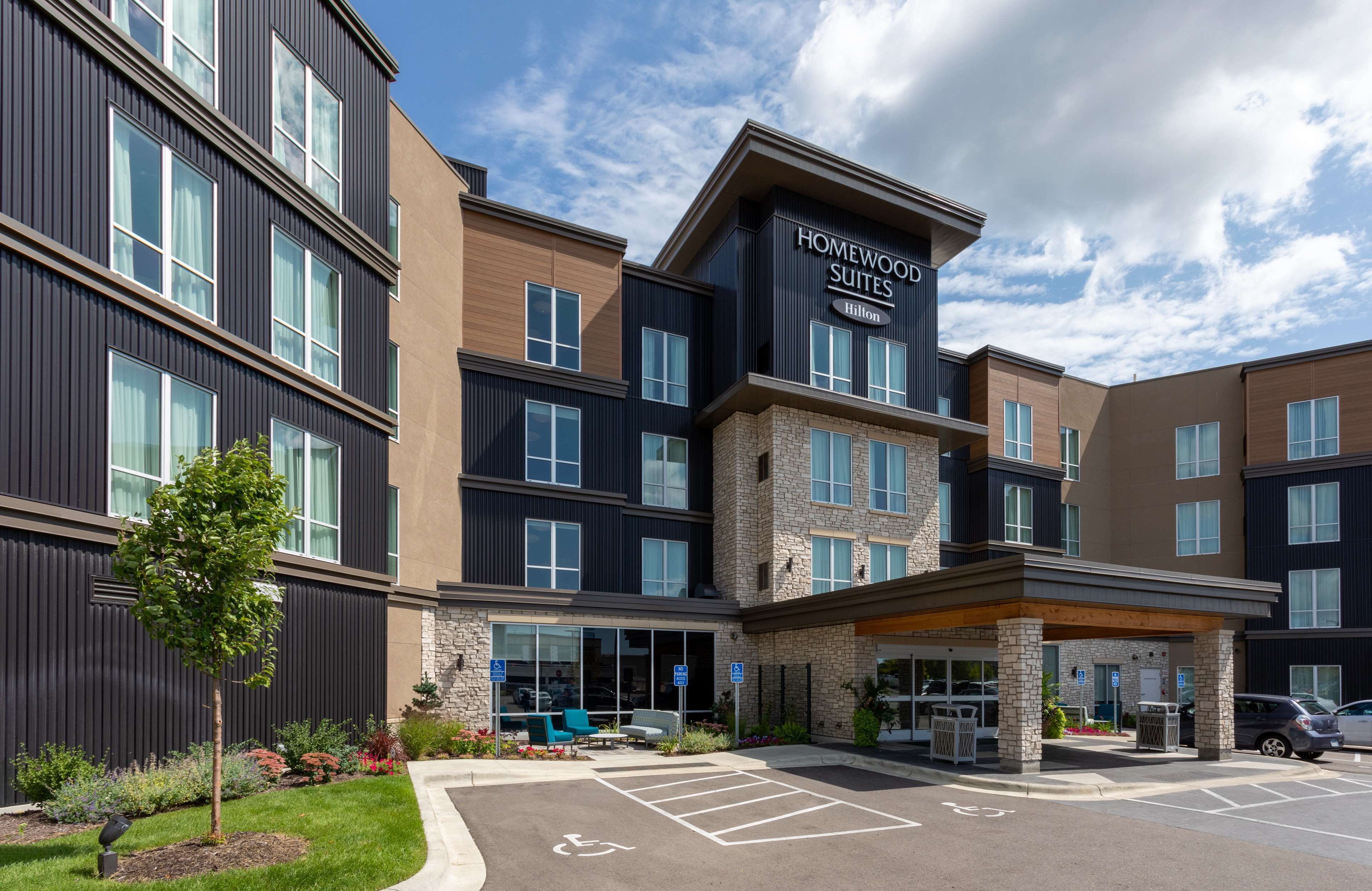 A modern hotel with a stone facade, multiple floors, and a covered entrance area.