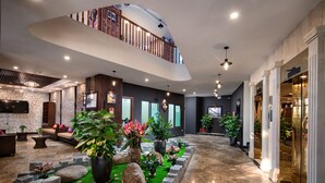 A spacious lobby with a high ceiling, a central garden area, and a mezzanine level. - The View Sapa Hotel (Sa Pa)