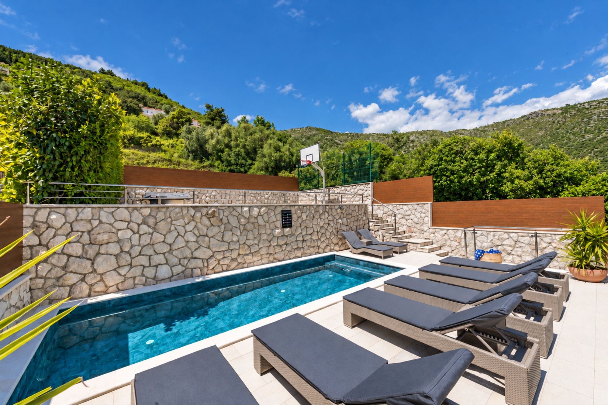 A swimming pool with lounge chairs and a stone wall.
