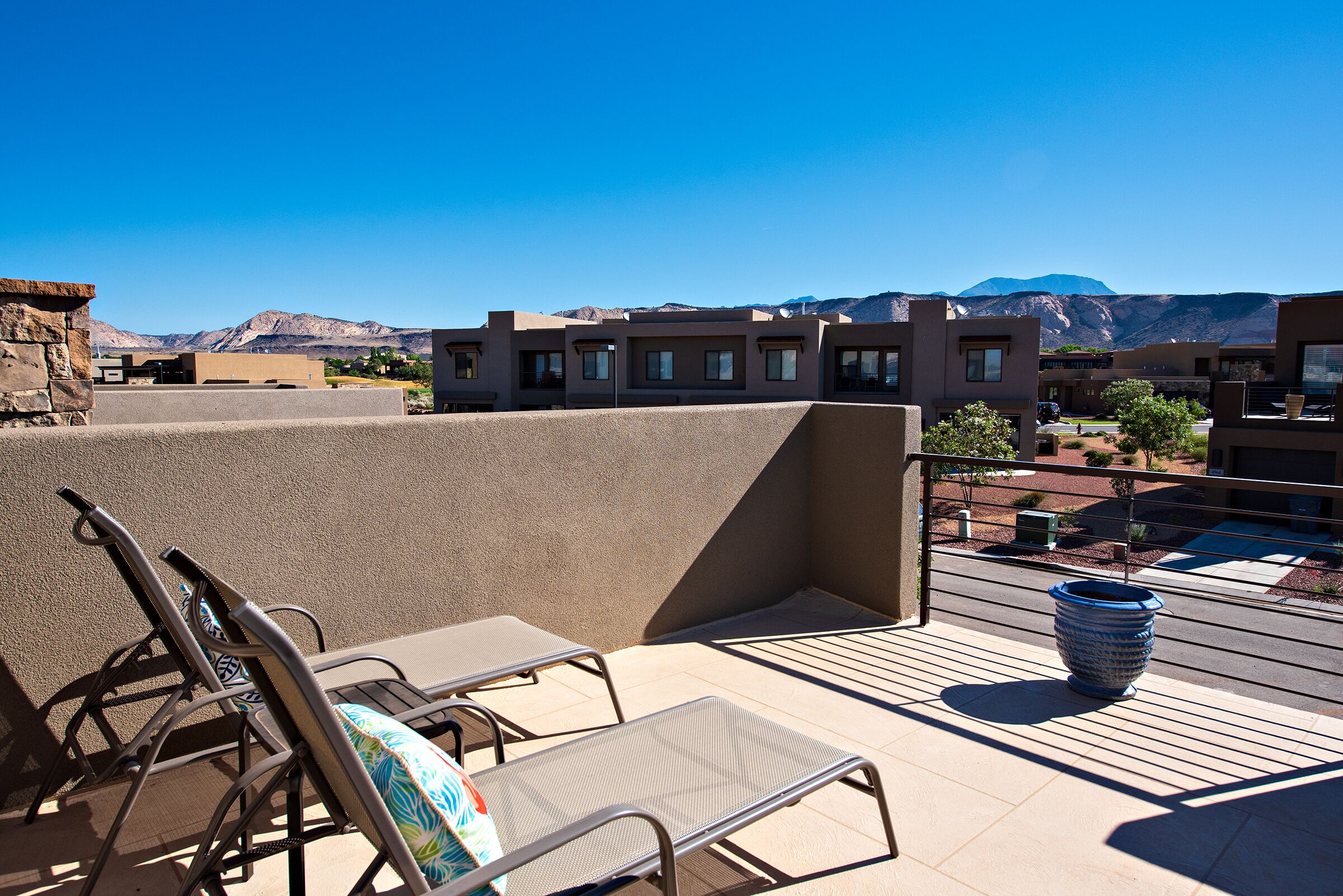 A rooftop terrace with lounge chairs and a large decorative pot.
