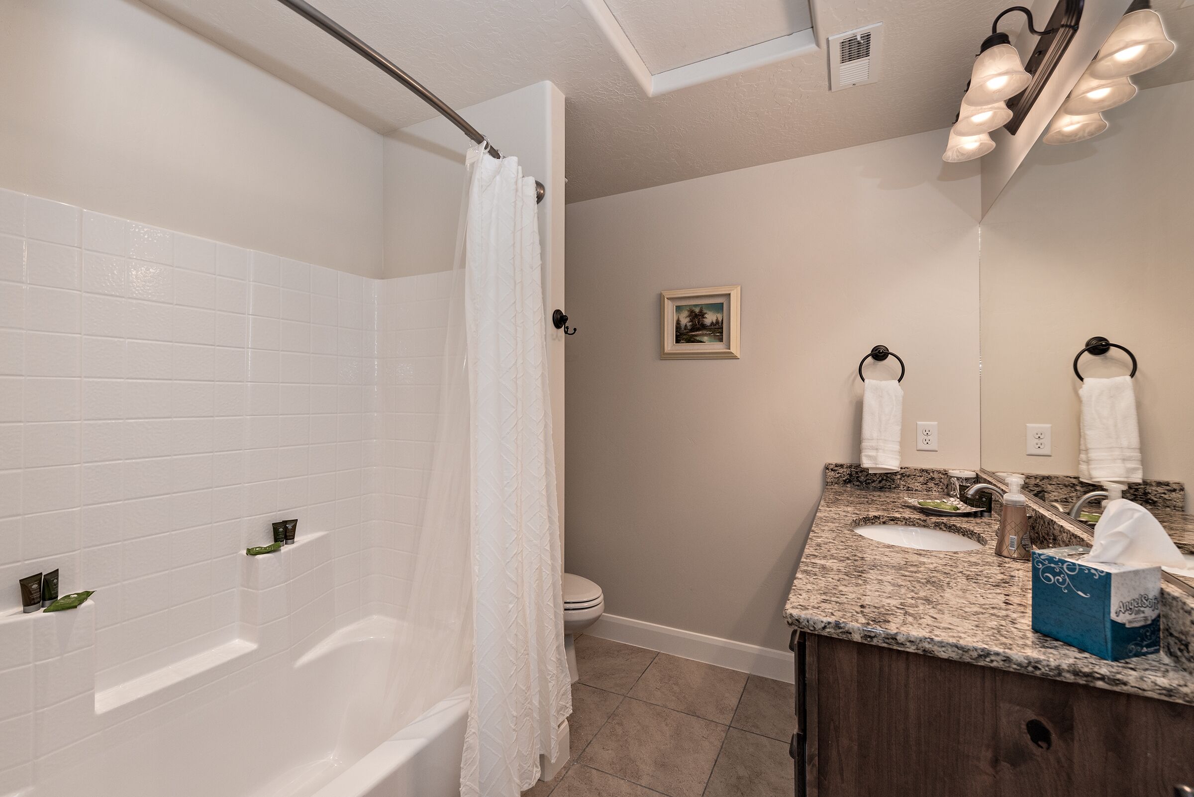 Une salle de bain comprenant une baignoire, des toilettes, un lavabo avec un miroir et un porte-serviettes.