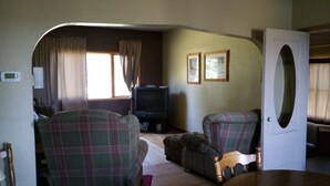 A living room with plaid chairs, a television, and a door with an oval window.