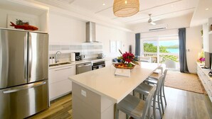 Una cocina moderna con una isla central, electrodomésticos de acero inoxidable y vistas al exterior.