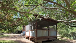Een houten vakantiehuisje met een overdekt terras, omringd door bomen.