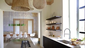 Une cuisine moderne avec un îlot central, des meubles noirs et des bouteilles en verre vert suspendues.