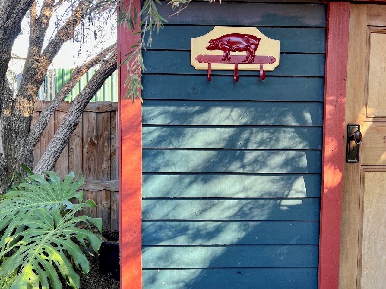 A blue door with a red trim, a wooden fence, and a tree.