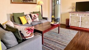 Una sala de estar con un sofá gris, una mesa de centro de madera y un mueble con televisor.