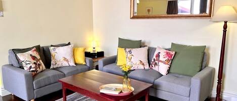 A living room with a grey sofa set, a wooden coffee table, and a patterned rug.