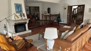 Un salon avec une cheminée, un canapé, une table basse et un fauteuil à bascule.