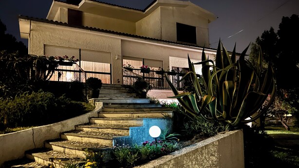 Une maison moderne avec un escalier bien éclairé menant à un porche abrité.