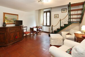 A living room with a wooden cabinet, a television, a dining table with chairs, a staircase, and a white sofa. - L'Antico Giglio - Sweet Dreams in Florence (Firenze)