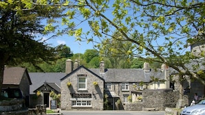 A stone building with a 'Welcome' sign and 'The Old Inn' sign, featuring a traditional architectural style with multiple windows and a stone facade. - Cosy holiday cottage in the National Park with stunning views and new kitchen. (Widecombe in the moor)