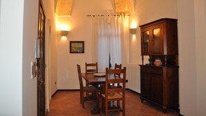 A dining area with a table and chairs, a cabinet, and a window with curtains. - Beautiful, romantic and central (Lecce)