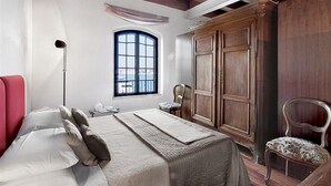 Une chambre avec un grand lit, une fenêtre donnant sur un beau paysage, une armoire et une chaise.