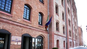 Un bâtiment historique en briques, doté de fenêtres en arc de cercle et d’un mât pour drapeau.