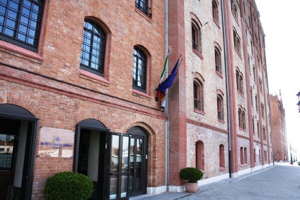 Un edificio histórico de ladrillo con ventanas de arco y un asta de bandera.
