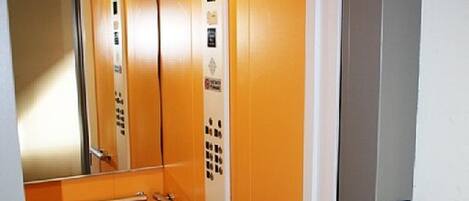 An elevator with orange walls, a control panel, and a handrail.