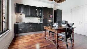 Une cuisine moderne avec des meubles de rangement sombres, une table à manger en bois et une porte blanche.