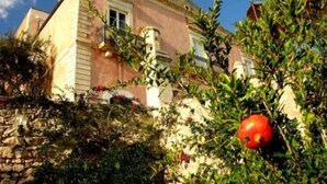 Un bâtiment à la façade rose, avec une fenêtre et un mur en pierre.