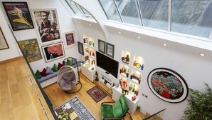 A modern living room with a high ceiling, skylight, and a flat-screen TV. - Chelsea Artist's Studio, by Veeve (London)