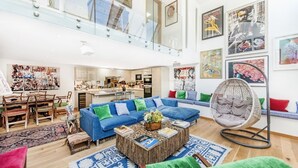 A spacious living area with a blue sofa, a round coffee table, and a hanging chair. - Chelsea Artist's Studio, by Veeve (London)