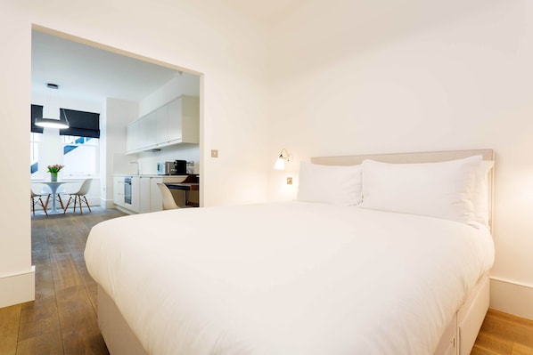 Et moderne hotelværelse med en stor seng, et lille tekøkken og et spiseområde med bord og stole.