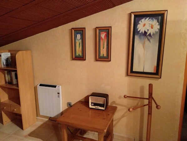 A room with a wooden table, a radiator, and three framed paintings on the wall. - Rural House Los Corteses (CARTAGENA)