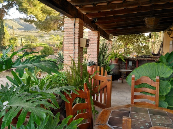 A covered patio area with brick pillars, wooden chairs, and a tiled table. - Rural House Los Corteses (CARTAGENA)