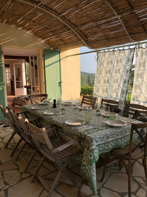 An outdoor dining area with a bamboo roof, a table set for six with chairs, and a view of greenery in the background. - Charming villa in Claviers with private pool and astonishing view  (Claviers)