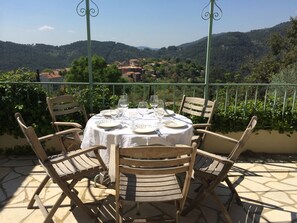 A round table with a white tablecloth set for four, surrounded by wooden chairs on a balcony with a view of a village and hills in the background. - Charming villa in Claviers with private pool and astonishing view  (Claviers)