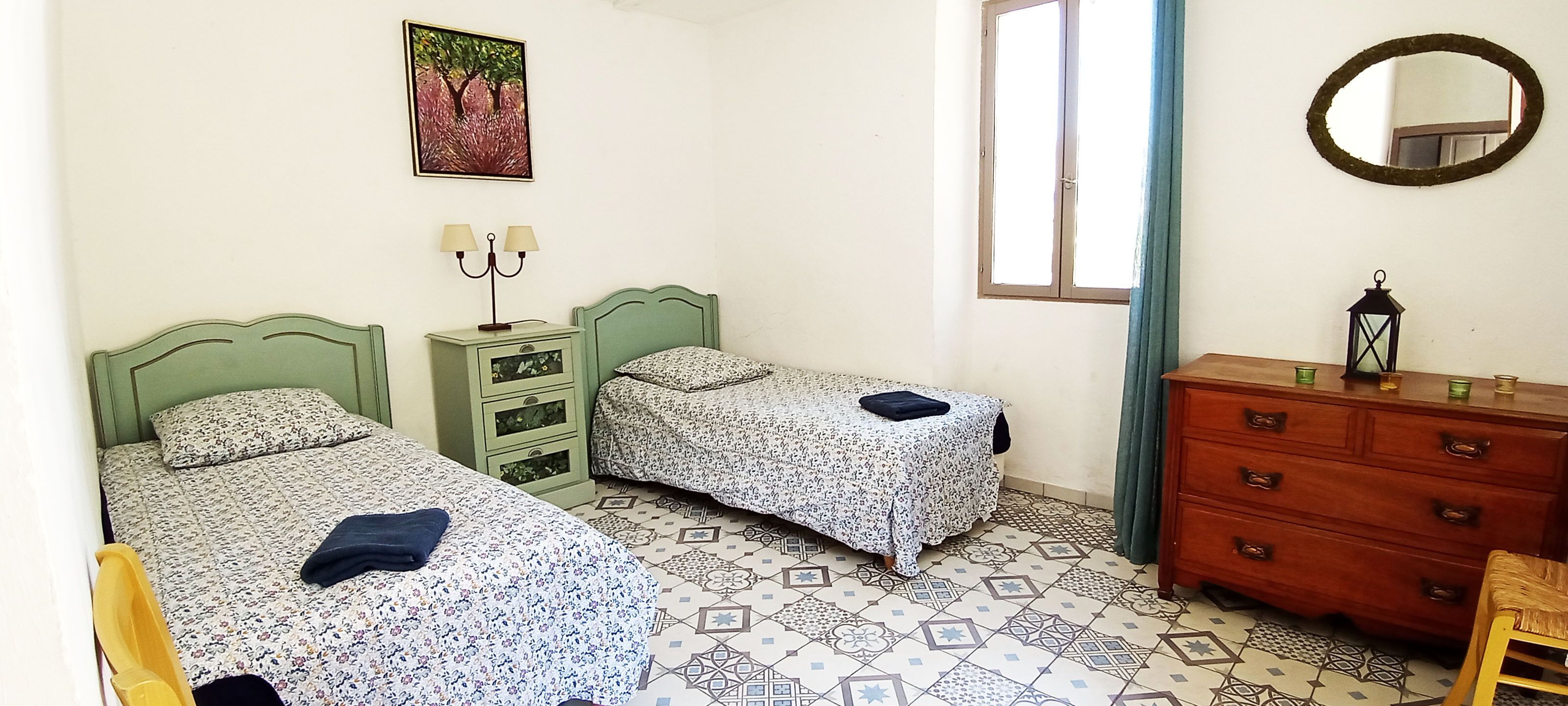 Un dormitorio con dos camas, un aparador, un espejo y una ventana con cortinas.