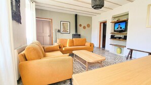 Una sala de estar con un sofá, una mesa de madera y un televisor sobre una estantería.