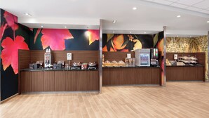 Zona de recepción con mostrador de madera, máquina de café y una bandeja con pasteles.