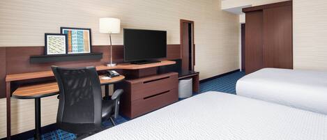 Een hotelkamer met een bed, een bureau met stoel, een televisie, een lamp en een kledingkast.