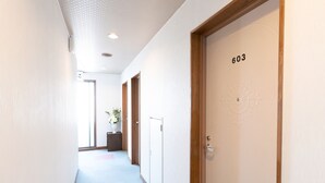 A hallway with a wooden door labeled "603" and a small plant on a table. - Business Hotel Apple (Nagoya)
