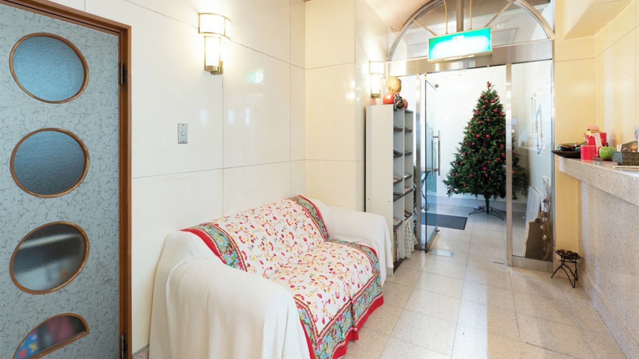 A hotel lobby with a white sofa, a Christmas tree, and a reception desk.