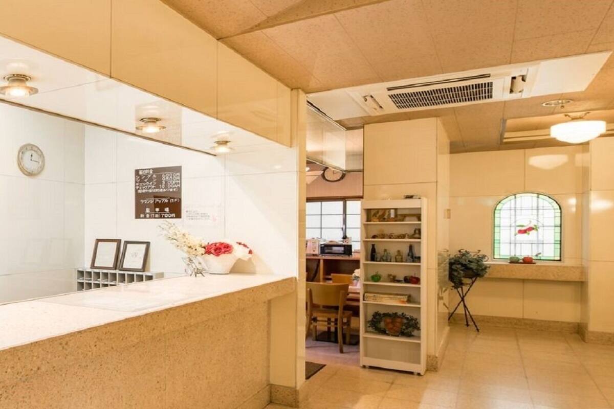 A reception area with a counter, a clock, a bulletin board, and a window with a view.
