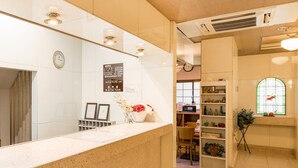 A reception area with a counter, a clock, a bulletin board, and a window with a view of the outside. - Business Hotel Apple (Nagoya)
