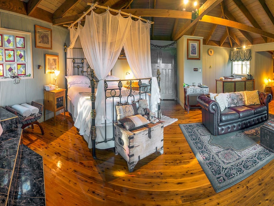 A cozy room with a large bathtub, a wooden floor, a comfortable sofa, and a dining area with a table and chairs.