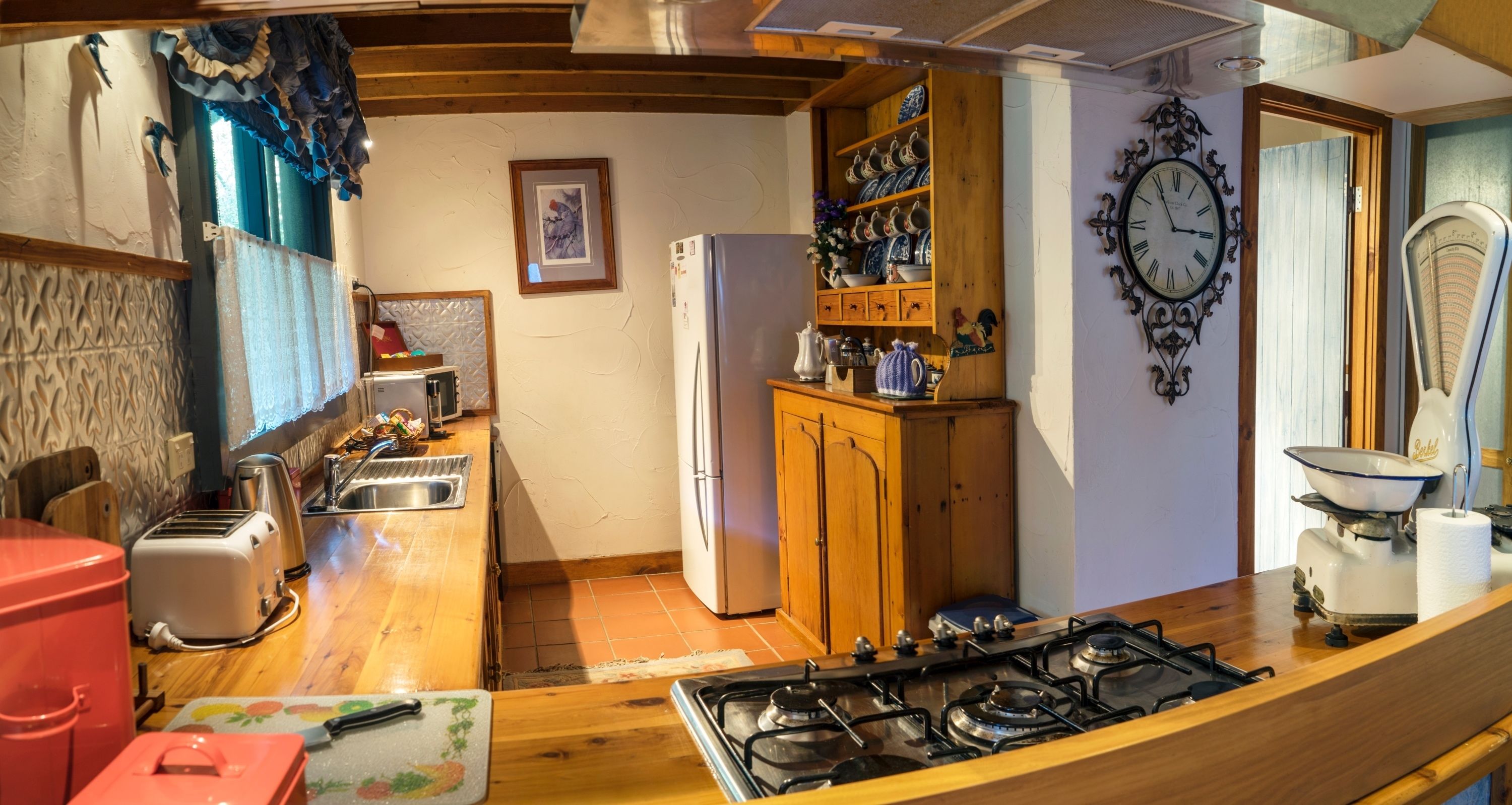 A kitchen with a wooden countertop, a gas stove, a refrigerator, and a sink.