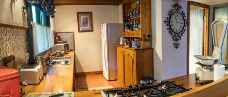 A kitchen with a wooden countertop, a gas stove, a refrigerator, and a sink.