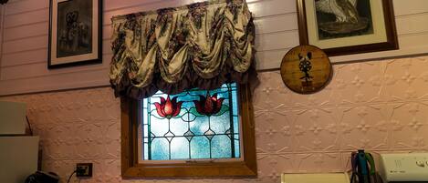 Una cocina con lavamanos, estufa y ventana decorativa con vidrieras.