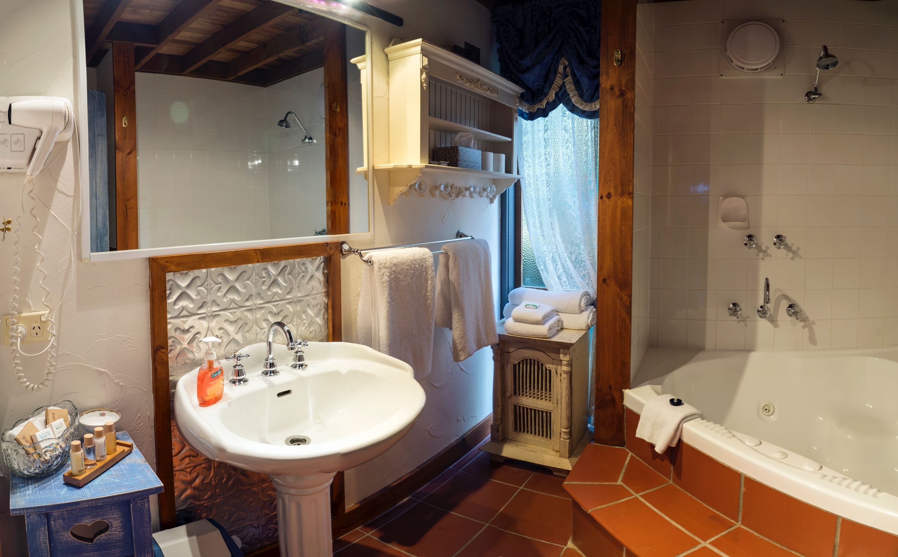 A bathroom with a sink, mirror, vanity, towel rack, shower, and bathtub.