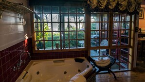 Een badkamer met een ruime badkuip, een raam met uitzicht op de omgeving, en een stoel bij het raam.