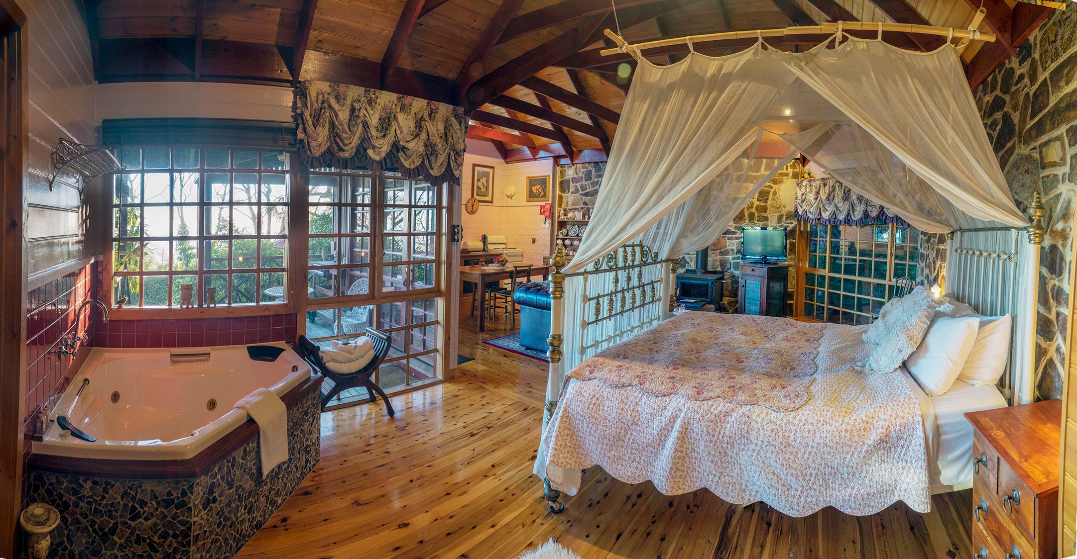 Une chambre à coucher avec un lit à baldaquin, une cheminée en pierre et une grande fenêtre.