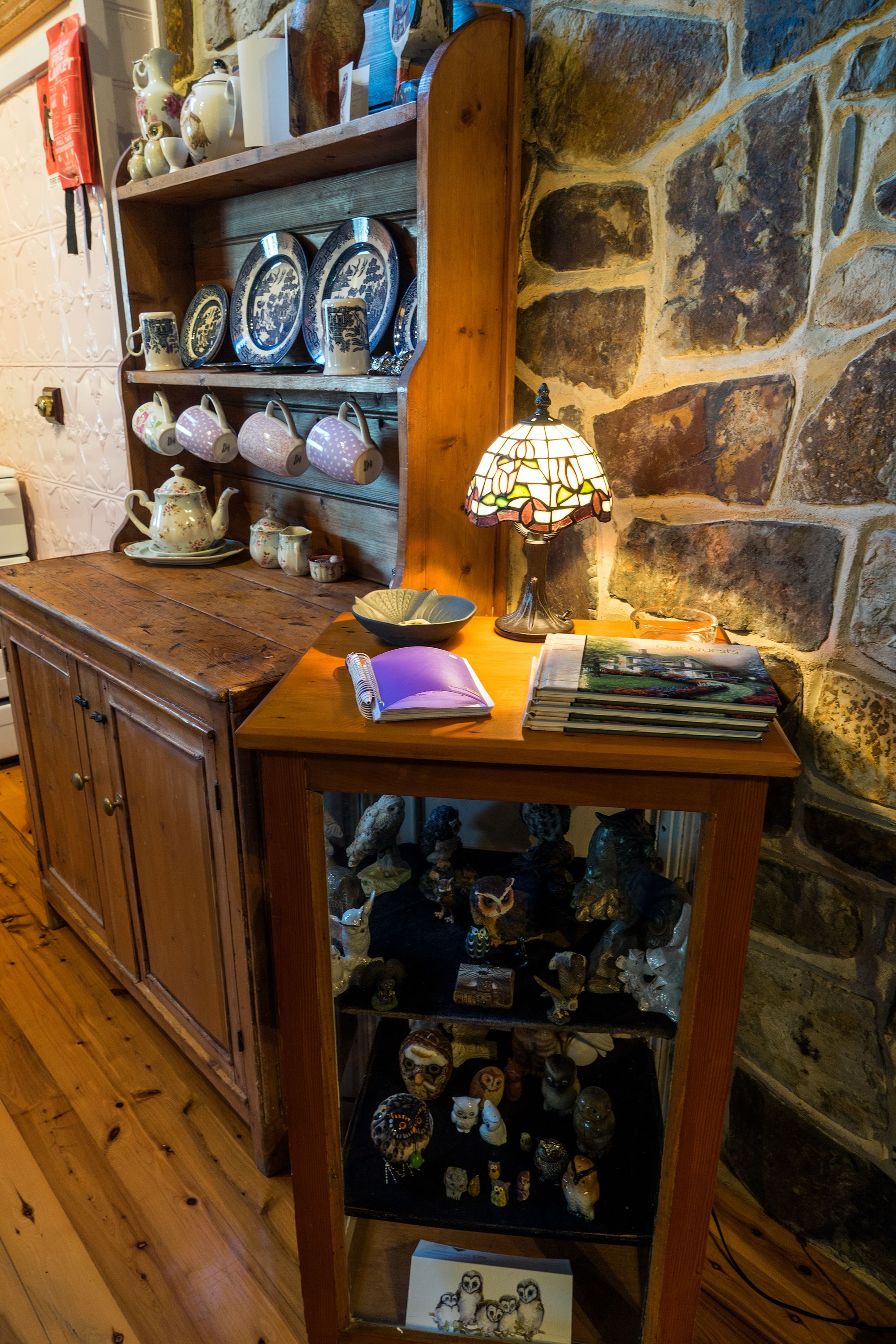 Una mesa de madera con una lámpara de vitral, una pila de libros y un tazón.