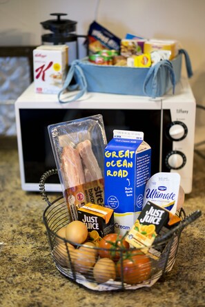 A kitchen counter with a basket of fresh produce, a carton of milk, and various food items. - Observatory Cottages (Mount Dandenong)