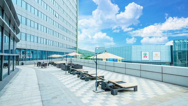 Une terrasse sur le toit avec des sièges en plein air, un sol à carreaux et un bâtiment moderne en arrière-plan.
