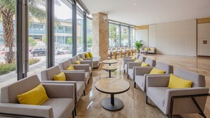 Un hall d’entrée moderne, doté de sièges et de tables, de grandes fenêtres et offrant une vue sur la rue.